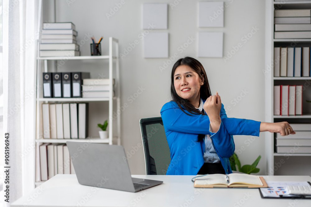 A woman in a blue jacket is stretching her arm in front of a laptop A woman in a blue jacket is stretching her arm in front of a laptop