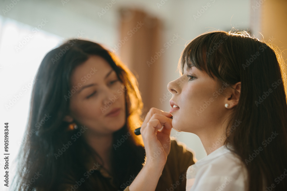 Beautiful female makeup artist doing makeup for a model in the studio before a photo shoot. Beautiful female makeup artist doing makeup for a model in the studio before a photo shoot.