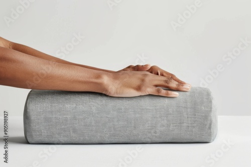 A person's hands gently adjust a yoga bolster to achieve the perfect position for support and comfort during a yoga practice. The bolster is placed under the knees or back for optimal alignment.