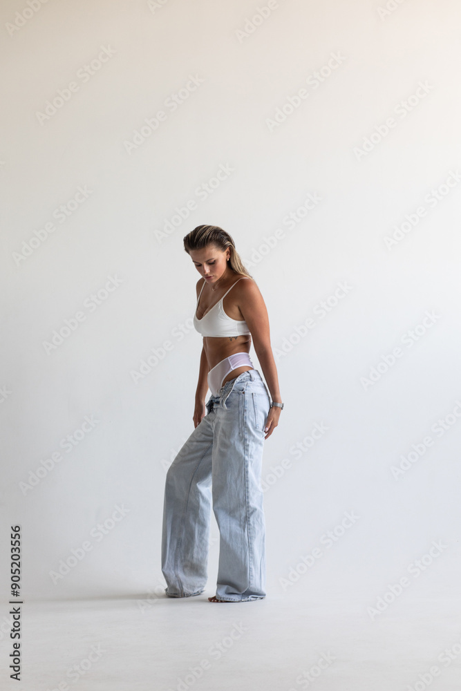 Beautiful blonde in white lingerie and jeans posing on white background Beautiful blonde in white lingerie and jeans posing on white background