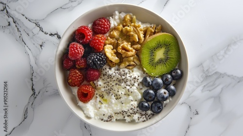 Breakfast cottage cheese with berries kiwi nuts and chia seeds in a white bowl top view