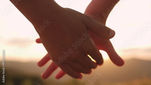 Silhouette of children holding hands on background mountains and colorful sky at warm sunset. Happy family together concept