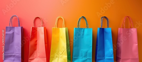Rainbow of colorful shopping bags against a vibrant orange background. Concept of shopping, retail, consumerism, LGBTQ+ pride, diversity, and sales.