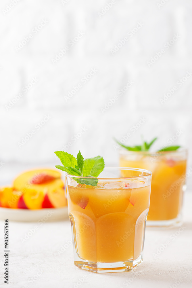 Fototapeta premium Peach and nectarine ice and mint lemonade on a light background. Homemade cold summer drink. Vertical orientation.