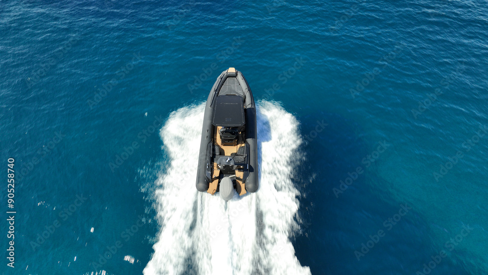 Aerial drone high speed tracking shot of inflatable rigid power boat cruising in high speed in Mediterranean deep blue sea bay