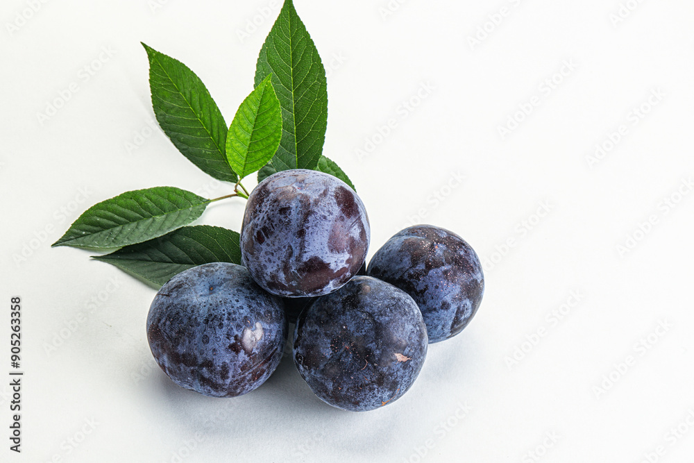 Raw purple plums heap with leaves Raw purple plums heap with leaves