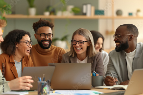 A diverse group of young professionals collaborating at a table with laptops and documents.  smiling and engaged, a positive and productive work environment. A modern office setting