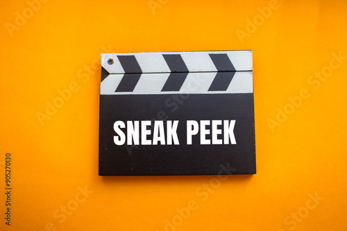 Sneak peek message written on movie clapper board with orange background. Conceptual sneak peek symbol. Copy space.