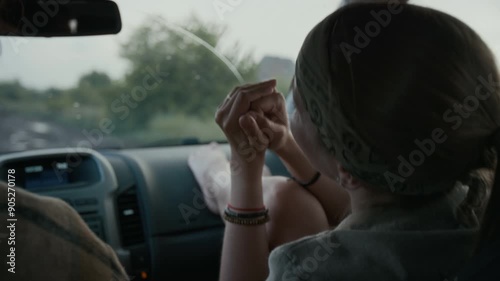 Wallpaper Mural Medium rear shot of happy Caucasian girl driving in car with boyfriend in countryside during rain, sitting with feet on dashboard, singing along to music on radio, while traveling on holiday Torontodigital.ca