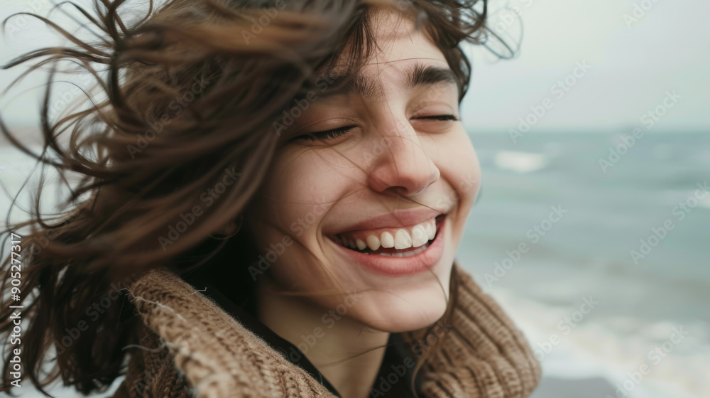 A young woman experiencing pure joy as she laughs with closed eyes on a breezy coastline, her hair caught in the wind. A young woman experiencing pure joy as she laughs with closed eyes on a breezy coastline, her hair caught in the wind.