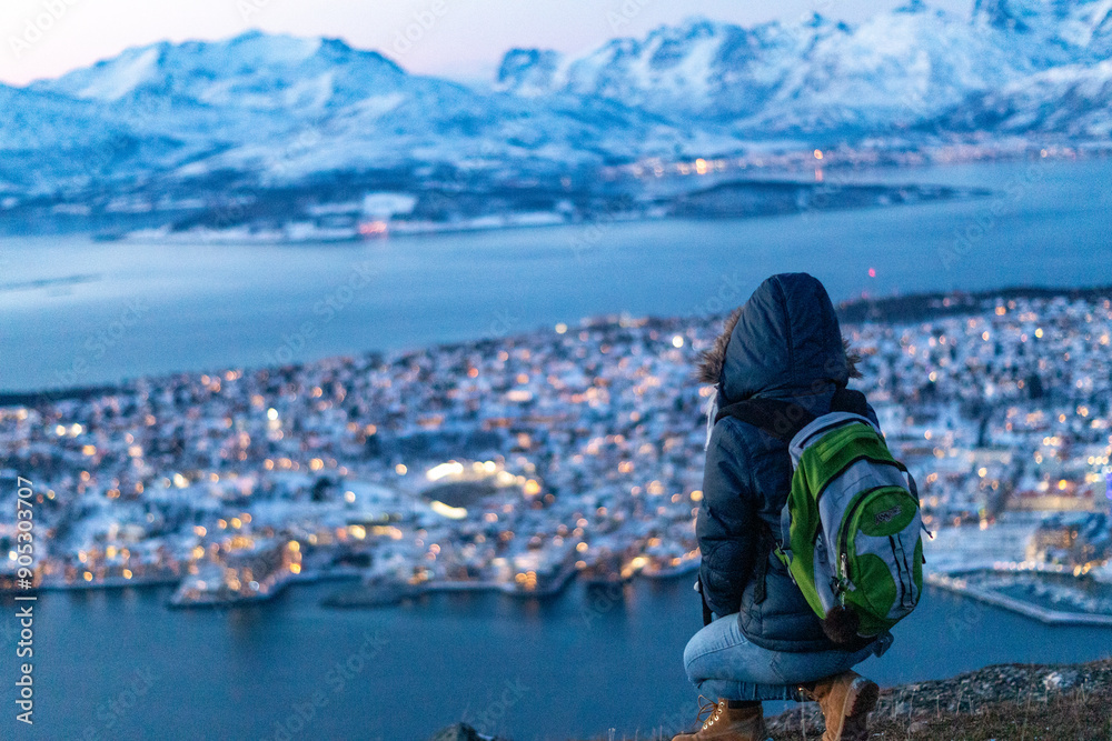 Obraz premium a blonde female woman traveler on top of the mountain in tromso norway in winter