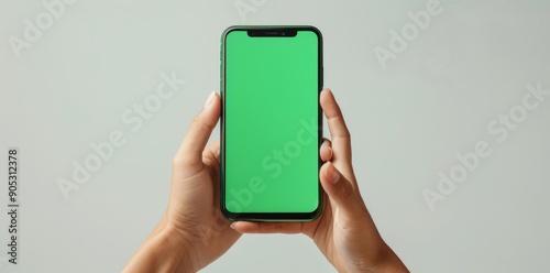 Hand holding smartphone with blank green screen, isolated on white background
