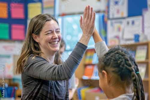 Obraz na płótnie A happy elementary school teacher gives a high-five to a smiling student during class. w salonie