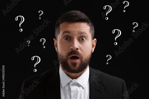 Shocked man and question marks on black background