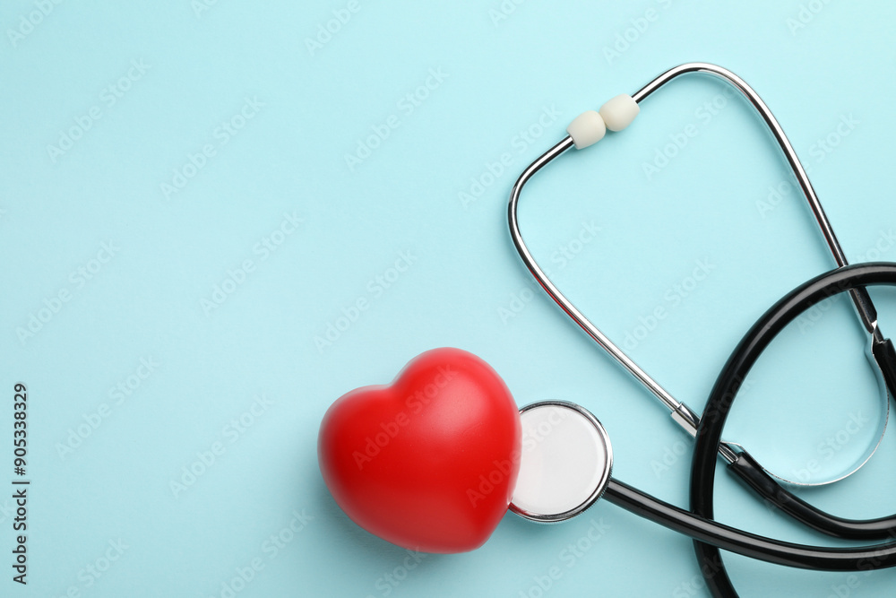 Stethoscope and red heart on light blue background, top view. Space for text Stethoscope and red heart on light blue background, top view. Space for text