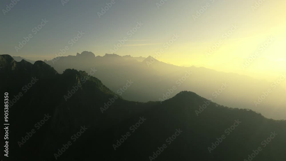 Drone view of silhouetted Italian Alps at dawn with misty sky in the background