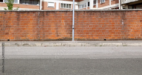 Street pole and brick wall at the roadside. Brick building on behind, sidewalk and road in front. Background for copy space. photo