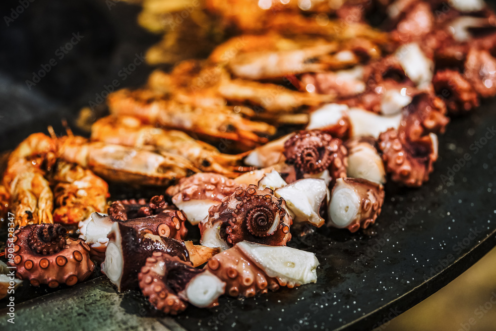 Cooking shrimp, octopus and sausage on a large grill