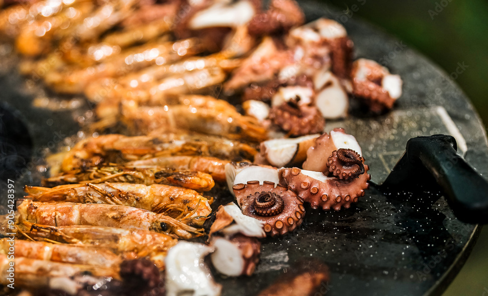 Cooking shrimp, octopus and sausage on a large grill