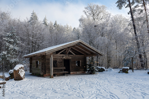 A wooden hut in winter with snow and trees