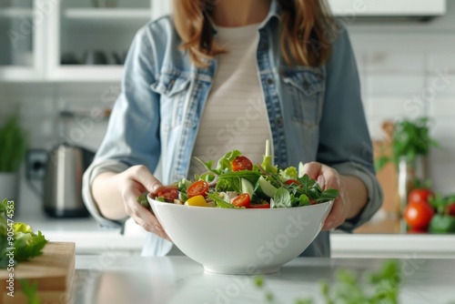 Woman prepares a delicious salad from fresh vegetables in a bright modern kitchen. Close-up. Healthy nutrition concept