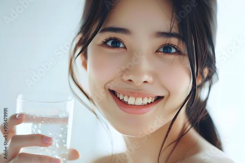 Close up beautiful smiling Asian woman holding glass of water isolated on white background