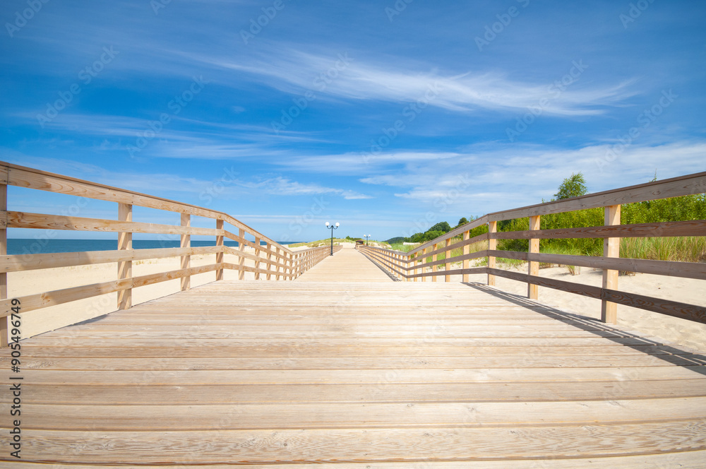 Fototapeta premium Wooden pathway on a sand beach in bright sunny day