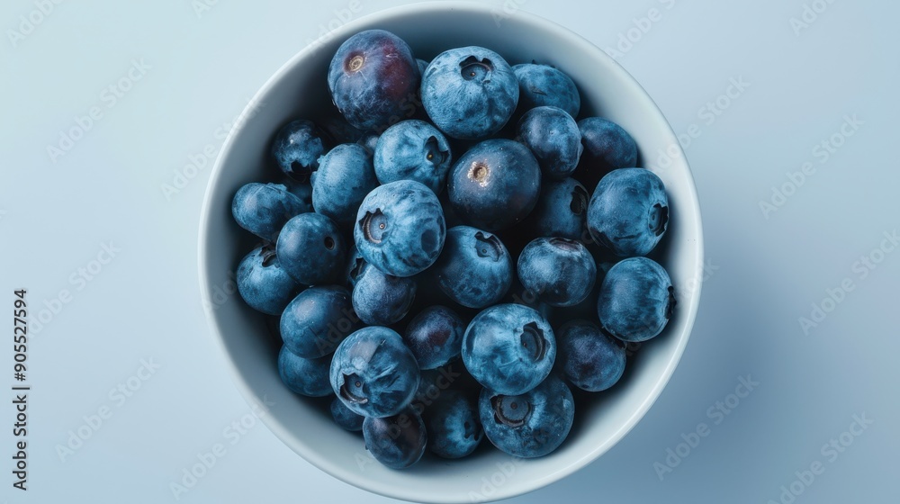 A bowl of blueberries is shown on a white background A bowl of blueberries is shown on a white background