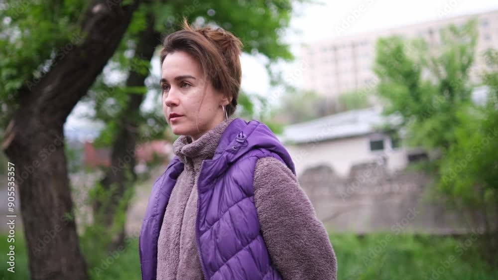 young woman with short brown hair, wearing a purple jacket. She displays various expressions while standing outdoors on a city street with a blurred, green backdrop young woman with short brown hair, wearing a purple jacket. She displays various expressions while standing outdoors on a city street with a blurred, green backdrop