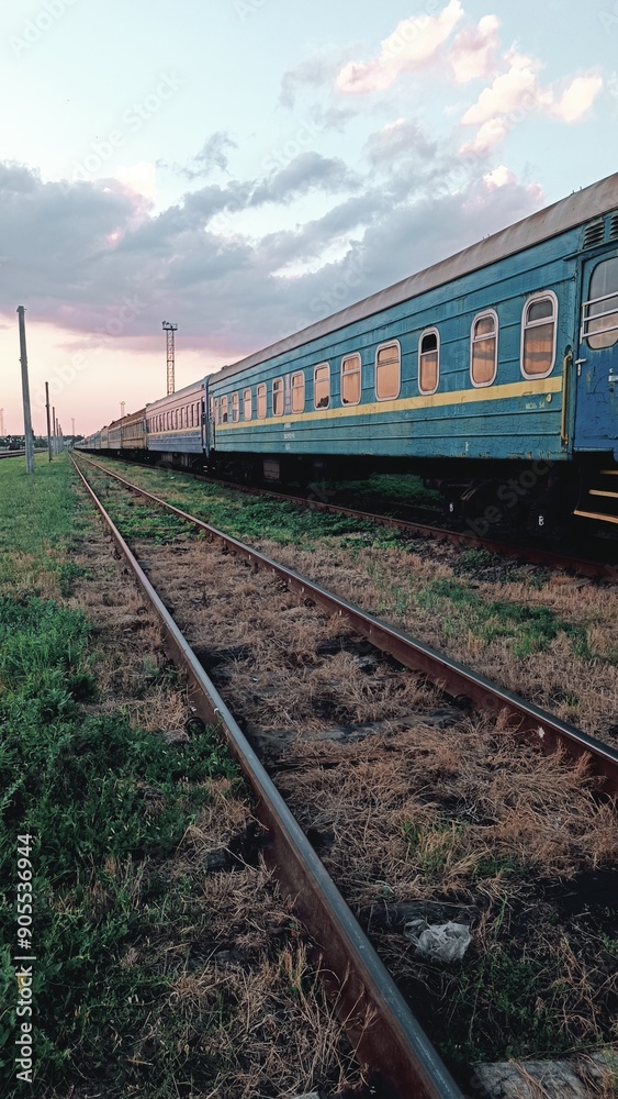 Fototapeta premium An old railway track with several blue passenger cars standing on the rails