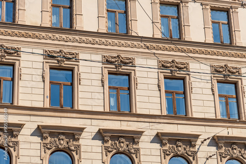 Side view of traditional ornate beige coloured facade with group of windows on wall of residential building in Saint Petersburg, Russia. Copy space. Architecture and city street background theme.