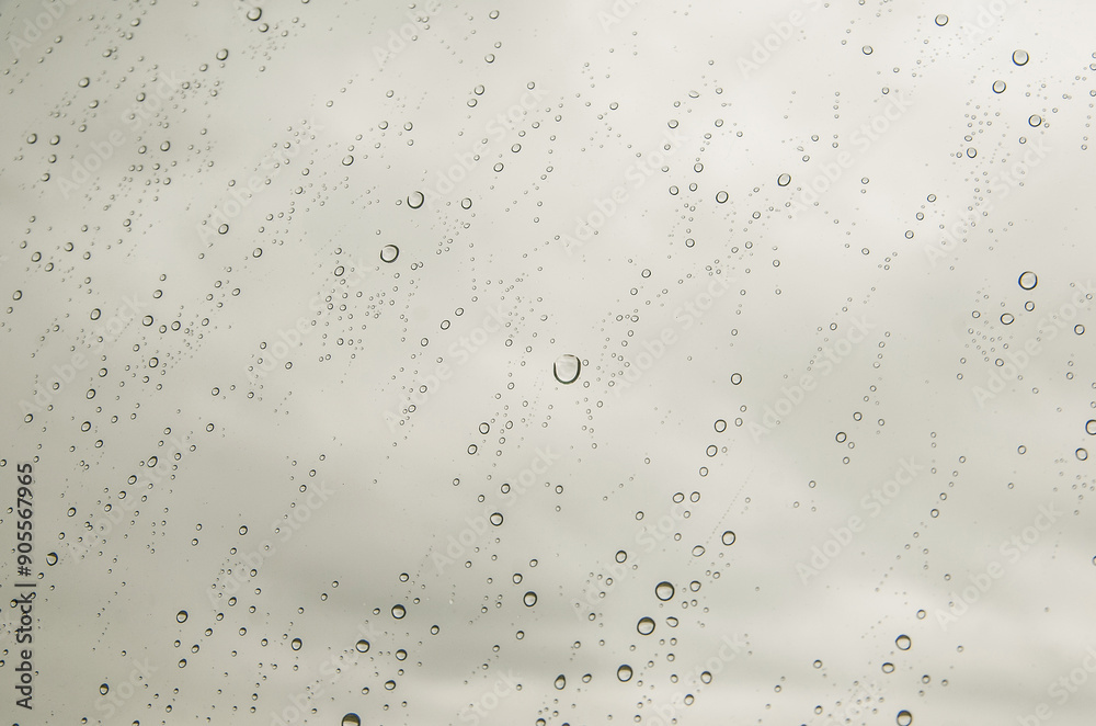 Raindrops and water drops on window glass in daytime and at sunset as background. Raindrops and water drops on window glass in daytime and at sunset as background.