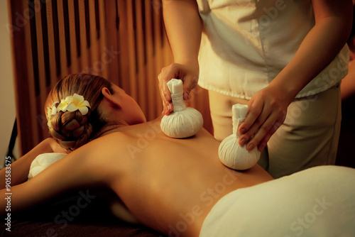 Wallpaper Mural Hot herbal ball spa massage body treatment, masseur gently compresses herb bag on woman body. Tranquil and serenity of aromatherapy recreation in warm lighting of candles at spa salon. Quiescent Torontodigital.ca