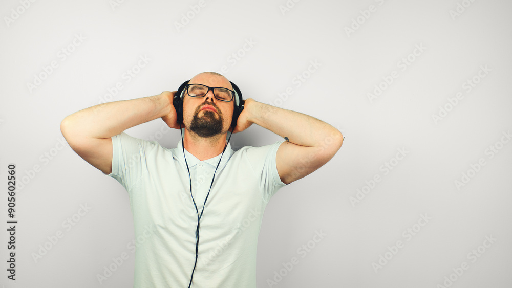 Portrait of handsome bearded man with glasses in white shirt, enjoying listening the music on headphones, lifestyle, isolated on white background Portrait of handsome bearded man with glasses in white shirt, enjoying listening the music on headphones, lifestyle, isolated on white background