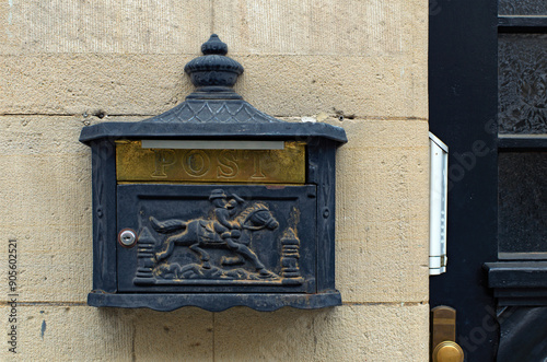 Traditional vintage post box on white plaster texture wall in Germany. Vintage metal mailbox with text “POST” in English language. Typical architecture in Bavaria, region Upper Franconia, Germany