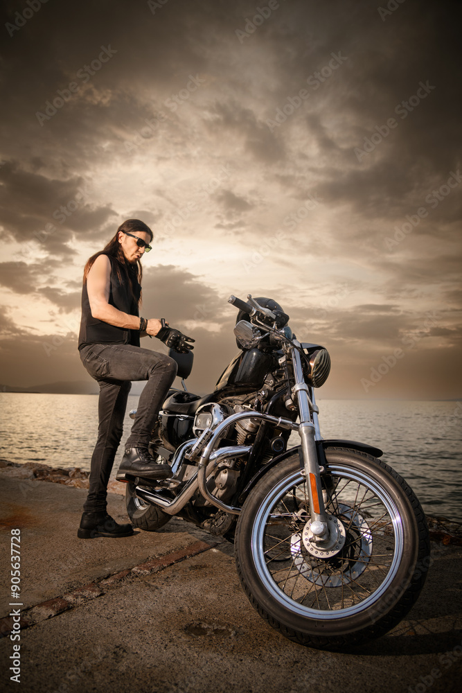 Fototapeta premium Man with Chopper Motorcycle by the Sea at Sunset..