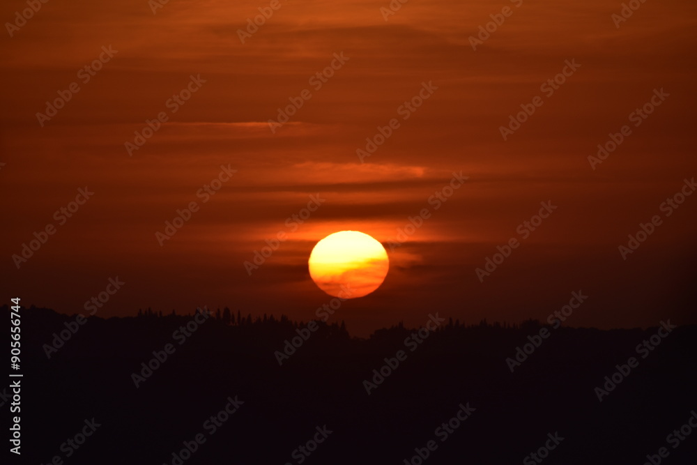Epic sunset landscape sky with big bright sun going behind the mountains in Greece Epic sunset landscape sky with big bright sun going behind the mountains in Greece
