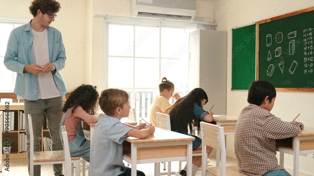 Skilled teacher walking at classroom while looking at student homework. Professional instructor checking smart children notebook while student doing test or working on homework at classroom. Pedagogy. Skilled teacher walking at classroom while looking at student homework. Professional instructor checking smart children notebook while student doing test or working on homework at classroom. Pedagogy.