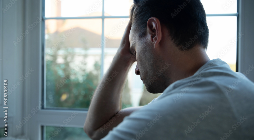 Depressed, sad, frustrated, crying, scared, instability mental and bipolar young man sitting on the windowsill at home. Headache because overworked and stress Depressed, sad, frustrated, crying, scared, instability mental and bipolar young man sitting on the windowsill at home. Headache because overworked and stress