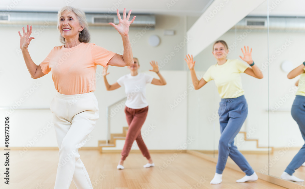 Obraz premium Woman dancing modern dance with other women during group training