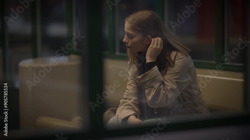 A woman sits by a window, lost in deep thought, reflecting solitude and introspection