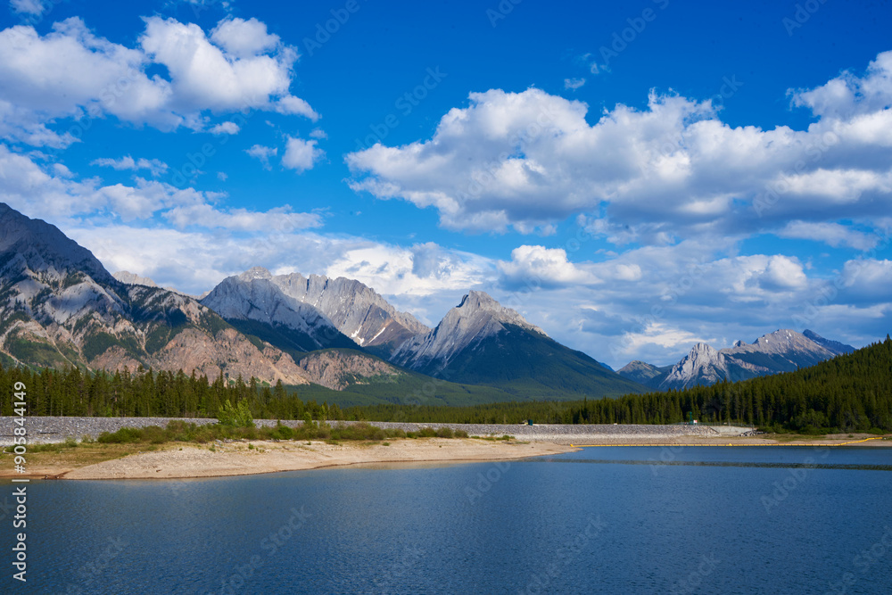 An incredible view of a natural mountain lake on a sunny summer day against the backdrop of the rocky mountains of Alberta in Canada.