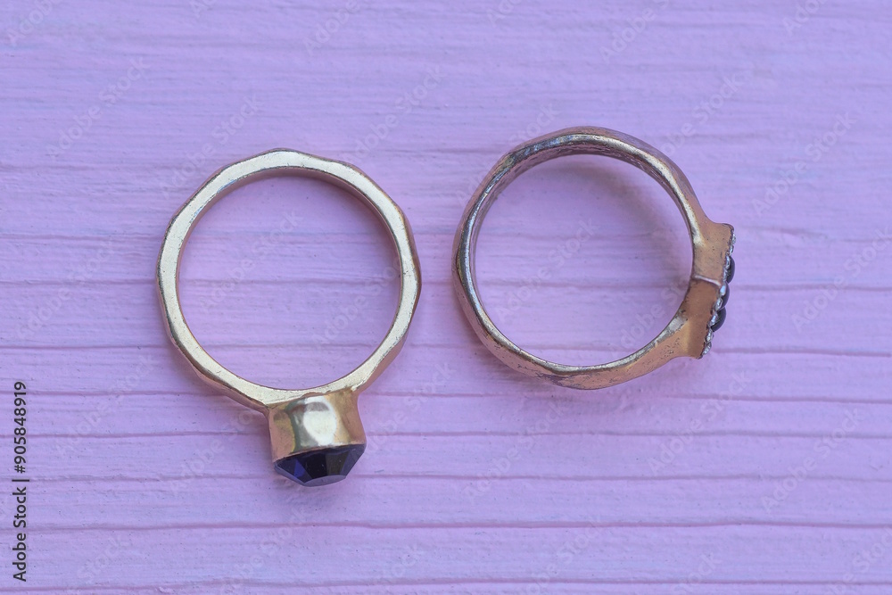 two yellow gold rings with stones lies on the pink table