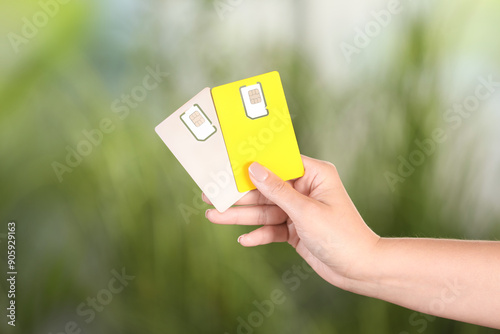 Woman holding SIM cards on blurred background, closeup