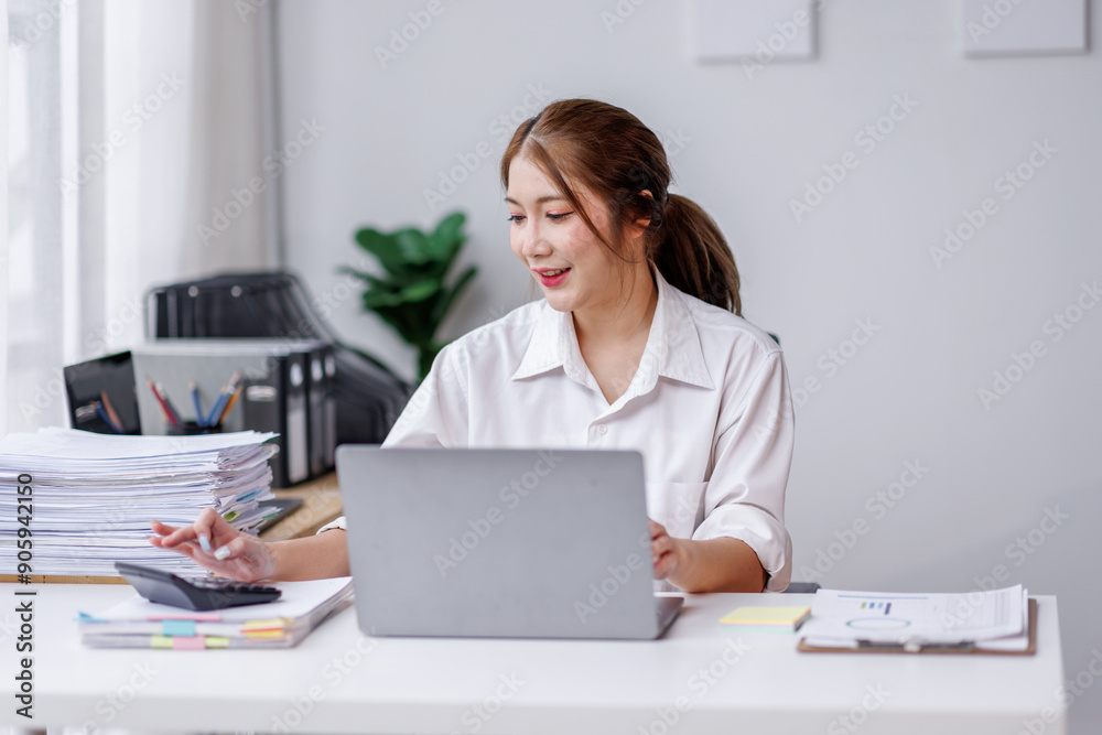 Young attractive business asian woman working of reading paper accounting file financial report, tax invoice on her documents project with laptop computer in the workplace office. Young attractive business asian woman working of reading paper accounting file financial report, tax invoice on her documents project with laptop computer in the workplace office.