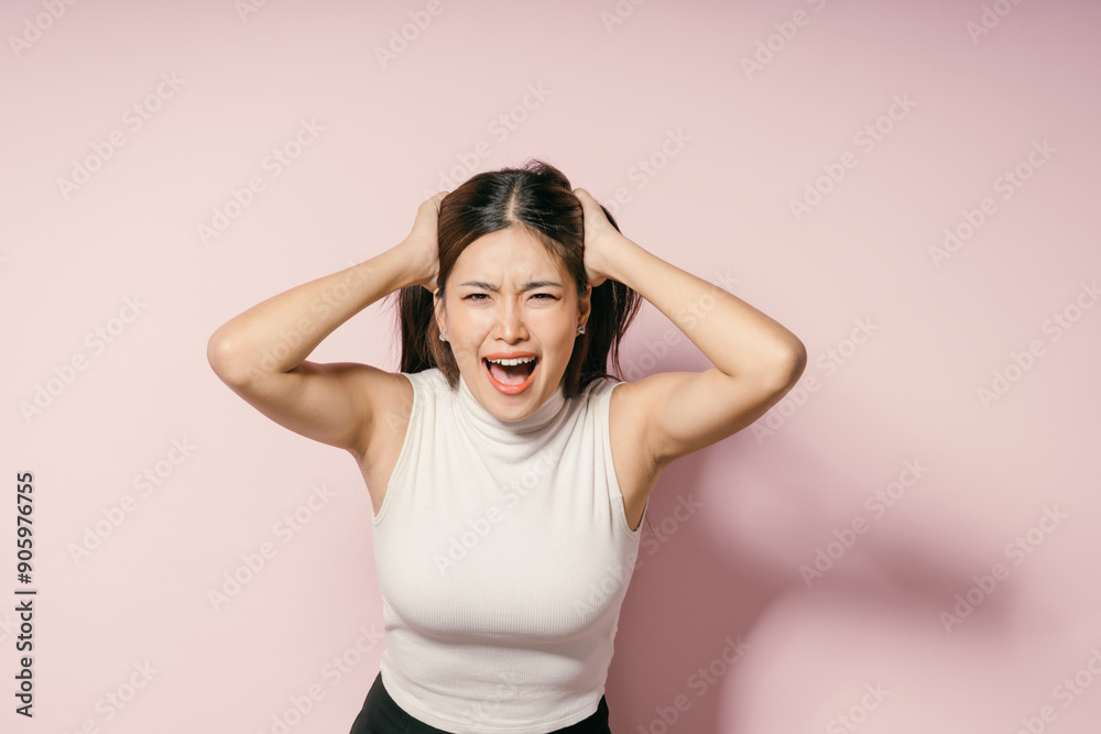 Frustrated Young Woman Pulling Hair and Screaming Against Pink Background in Studio Frustrated Young Woman Pulling Hair and Screaming Against Pink Background in Studio