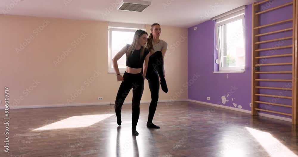 Two young women in black clothing practicing a contemporary ballet moves in a dance studio. Two young women in black clothing practicing a contemporary ballet moves in a dance studio.