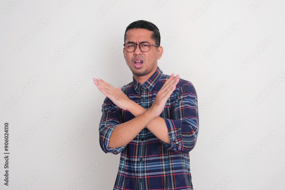 Adult Asian man showing worried expression while doing stop hand sign Adult Asian man showing worried expression while doing stop hand sign