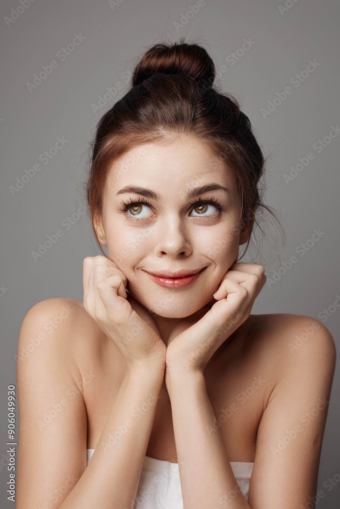Beautiful young woman with hands on chin, looking at camera, on gray background Beautiful young woman with hands on chin, looking at camera, on gray background