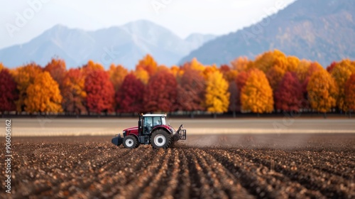 A tractor in a field with vibrant autumn trees in the background